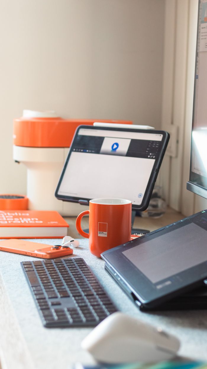 why-choose-us-02 A sleek workspace setup with orange accents, featuring a tablet, keyboard, and mug.