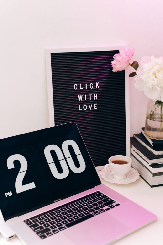 A chic workspace featuring a laptop, love quote board, and coffee with flowers.